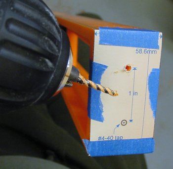Hand drilling the end of the level with a paper template taped on it.