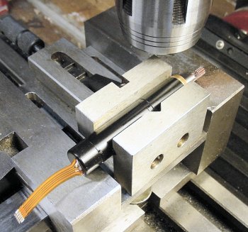 A miniature DC gearmotor held in a v-groove in a vise in a larger vise.